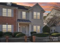 Two-story townhome with brick and siding exterior, featuring a gray door and a white picket fence at 6033 Creft Cir, Indian Trail, NC 28079