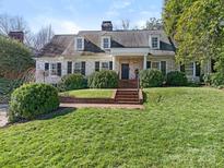 Charming white brick home featuring dormer windows, mature landscaping, and a welcoming front entrance at 1136 Bolling Rd, Charlotte, NC 28207