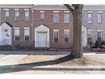 Charming brick townhome with a white door, decorative accents, and wrought iron railing in a residential setting at 135 Singleton Rd, Mooresville, NC 28117