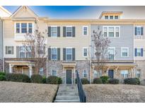 Two-story townhome with stone and siding exterior, landscaping, and a concrete walkway at 9115 Bluefield St, Charlotte, NC 28273