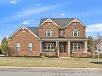 Inviting two-story brick home featuring a covered front porch and manicured landscaping at 120 Trelawn St, Fort Mill, SC 29715