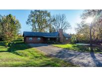 Inviting brown wood siding home with a covered porch and charming landscaping at 241 Pinecrest Ct, Taylorsville, NC 28681