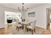 Dining area with chandelier, hardwood floors, neutral decor, and access to the living room at 3828 Chandworth Rd, Charlotte, NC 28210