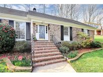 Charming brick home with manicured landscaping, steps to the front door, and a welcoming entryway at 3828 Chandworth Rd, Charlotte, NC 28210