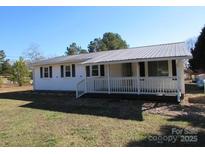 White ranch house with gray metal roof, front porch, and spacious yard at 1876 Rollins Dr, Catawba, NC 28609