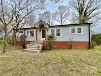 Charming single-story home featuring a brick foundation, light gray siding, and covered porch with wooden support beams at 400 E 27Th St, Kannapolis, NC 28083