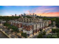 Modern apartment complex showcasing red brick and beige exterior with skyline views at sunset at 1315 East Blvd # 203, Charlotte, NC 28203