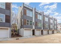 Modern townhome exterior with a brick and gray facade plus rooftop deck and attached garages at 5048 York Park Ln, Charlotte, NC 28217