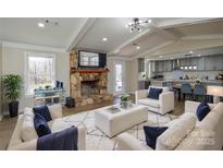 Inviting living room with a stone fireplace, wood floors, and an open floor plan to the modern kitchen at 6615 Love Mill Rd, Monroe, NC 28110