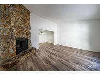 Spacious living room featuring a stone fireplace and laminate wood floors at 7151 Stonington Ln, Charlotte, NC 28227