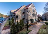 Charming condo complex with mature landscaping, sidewalks, and a striking metal roof at 9037 J M Keynes Dr # 23, Charlotte, NC 28262