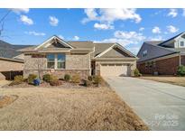 Charming single-story home featuring a brick and stone facade, attached garage, and well-maintained lawn at 9428 Liberty Hill Dr, Mint Hill, NC 28227