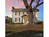 Two-story farmhouse with white siding, brown shutters, and a large tree in the front yard at 3433 Grey Rd, Davidson, NC 28036