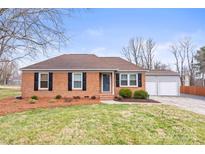 Charming brick home featuring dark shutters, manicured landscaping, and a detached two-car garage at 3521 Heather Ln, Gastonia, NC 28056