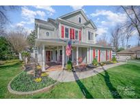 Charming two-story home with a covered front porch, American flag, and well-maintained landscaping at 10111 Grimsby Ct, Huntersville, NC 28078