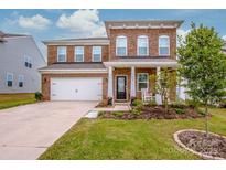 Two-story brick home with a front porch, two-car garage, and landscaped yard at 127 Doncaster Dr, Mooresville, NC 28115