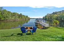 Beautiful lake view with a dock, enhanced by Adirondack chairs next to an outdoor fire pit at 3917 Acacia N Rd, York, SC 29745