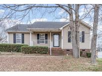 Tan one-story house with black shutters, small porch, and landscaping at 844 Turning Point Ln, Concord, NC 28027