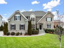 Charming home featuring a manicured lawn, stone accents, and a welcoming entryway with lovely landscaping at 8509 Penton Pl, Harrisburg, NC 28075