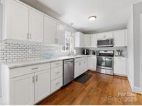 A bright kitchen featuring white cabinets, subway tile backsplash, stainless steel appliances, and hardwood floors at 1116 Circlewood Dr, Charlotte, NC 28211