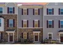 Townhome with stone and gray siding, burgundy shutters, manicured lawn, and covered front entry at 1419 Newell Towns Ln, Charlotte, NC 28262