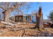 Exterior of home with covered porch and mature trees on an overgrown lot at 2021 Willis Dr, Shelby, NC 28152