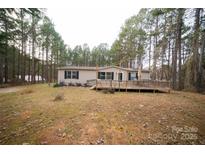 Tan mobile home with wooden deck, surrounded by trees at 210 Barbary Dr, Statesville, NC 28677