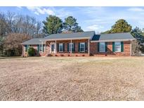 Charming brick home featuring green shutters, complemented by an expansive front yard at 101 Griffin St, Stanley, NC 28164