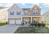 Two-story house with gray siding, stone accents, and a three-car garage at 10422 Ebbets Rd, Charlotte, NC 28273