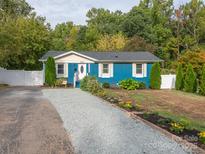 Cute blue house with gravel driveway, landscaping, and white fence at 1204 Allenbrook Dr, Charlotte, NC 28208