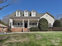 Charming two-story home with a welcoming front porch, manicured lawn, and classic architectural details under a clear blue sky at 4407 Esherwood Ln, Charlotte, NC 28270