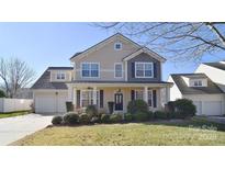 Two-story house with beige siding, two-car garage, and landscaping at 9806 Penn Station St, Cornelius, NC 28031