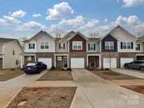 Charming townhome exteriors featuring brick accents and attached garages, set against a blue sky with lovely cloudscape at 14041 Castle Nook Dr # 75, Charlotte, NC 28273