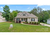 Charming one-and-a-half-story home with manicured lawn and stone accents at 704 Kenway Loop, Mooresville, NC 28117