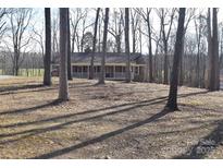 Brick ranch house with a covered porch, nestled among tall trees on a spacious lot at 1008 E Sandy Ridge Rd, Monroe, NC 28112