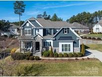 Two-story home with gray siding, stone accents, and a landscaped lawn at 100 S Centurion Ln, Mount Holly, NC 28120