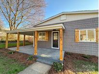 Charming single-Gathering home featuring a covered front porch with rustic wood columns and gray shingle siding at 1003 W 4Th Ave, Gastonia, NC 28052