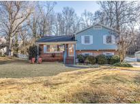 Ranch style home with brick and light blue siding, featuring a well-manicured lawn and mature trees at 1224 Castlegate St, Gastonia, NC 28054