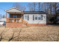 Gray siding house with brick base, wooden porch, and mature trees in the yard at 604 Kimball St, Kannapolis, NC 28081