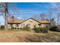 Charming single story home with brown siding, shutters, a well-manicured lawn, and mature trees at 7753 Old Post Rd, Denver, NC 28037