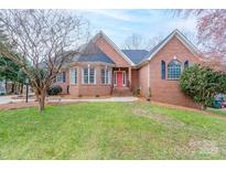 Charming brick home boasts a manicured lawn and inviting red door, complete with mature trees at 1915 Cavendale Dr, Rock Hill, SC 29732