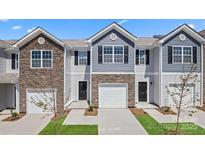 A modern townhouse exterior featuring a one-car garage, stone accents, and well-maintained landscaping at 3148 Ora Smith Rd, Lincolnton, NC 28092