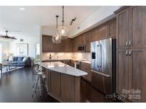 Modern kitchen featuring stainless steel appliances, wooden cabinets, and a stylish marble countertop island at 4620 Piedmont Row Dr # 504, Charlotte, NC 28210