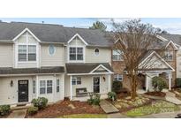 Tan two-story townhome with a covered porch and landscaping at 12250 Savannah Garden Dr, Charlotte, NC 28273