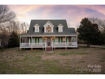 Two-story house with a wraparound porch and landscaped lawn at 2400 Potter Downs Dr, Waxhaw, NC 28173