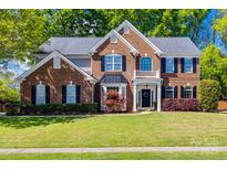 Beautiful brick two-story home featuring manicured lawn, well-maintained landscaping, and elegant architectural details at 11006 Knight Castle Dr, Charlotte, NC 28277