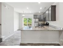 Modern kitchen with gray cabinets, granite counters, and stainless steel appliances at 7011 Jane Parks Way, Charlotte, NC 28217