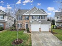 Two-story home featuring stone accents, two-car garage and well-manicured lawn under a bright blue sky at 10319 Barrands Ln, Charlotte, NC 28278