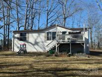 Single-wide mobile home with deck and playset, situated on a spacious lot with mature trees at 32139 Blakley Dr, Albemarle, NC 28001