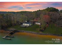 Stunning lakefront estate with private dock and lush landscaping at sunset offers serene waterfront living at 125 Chestnut Tree Rd, Mooresville, NC 28117